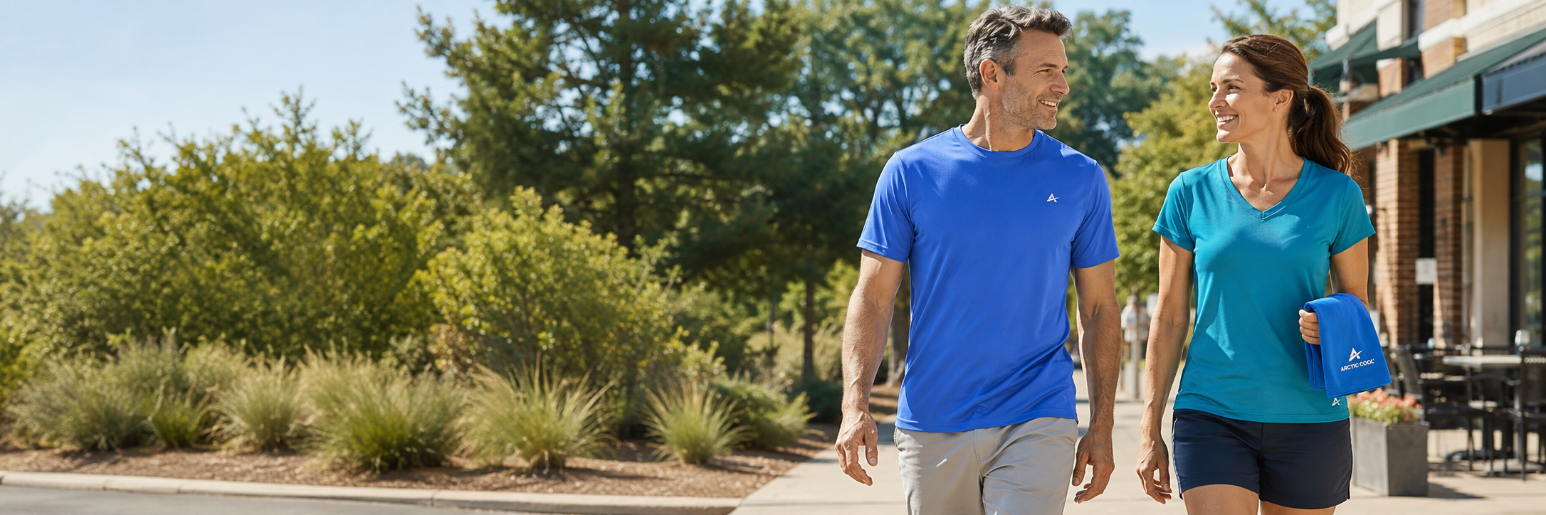 Man and woman wearing lightweight Arctic Cool clothing while walking outside during a hot August afternoon