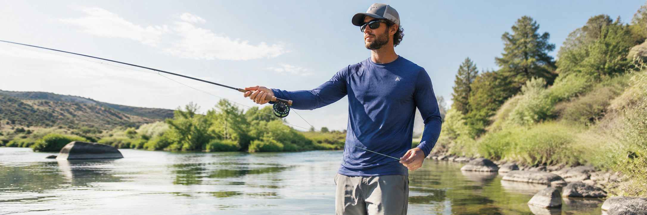 Man wearing an Arctic Cool long sleeve cooling shirt while fly fishing in a sunny river.