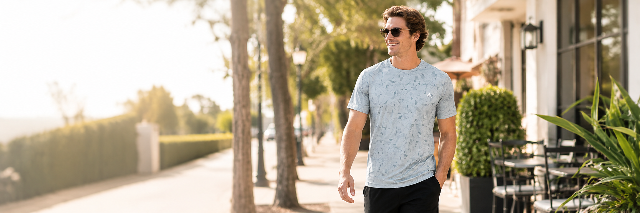 Man wearing a light gray Arctic Cool performance cooling shirt outdoors on a warm sunny day, shown in a clean premium lifestyle setting with natural sunlight and breathable summer atmosphere.